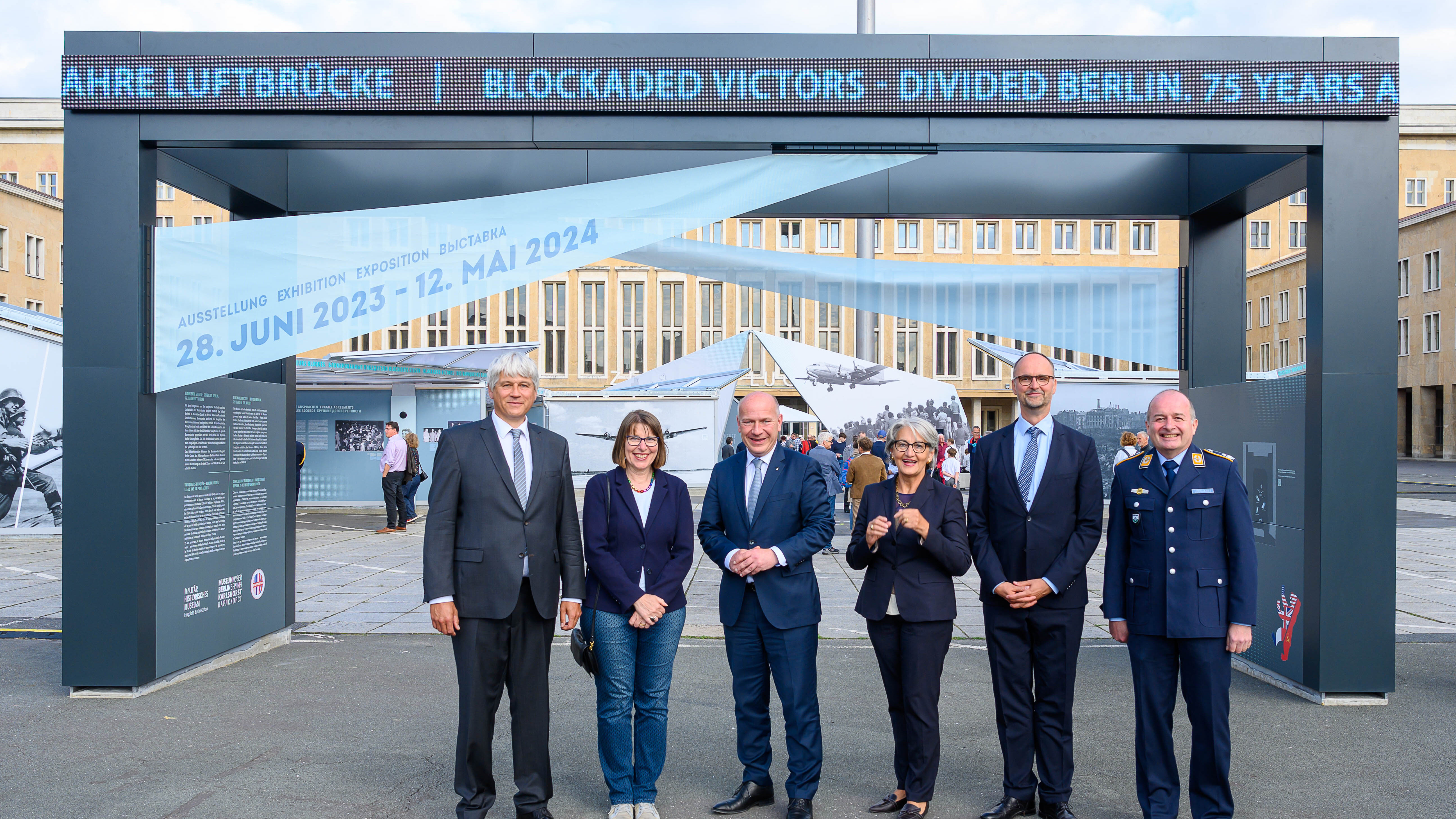 Eine Personengruppe steht vor dem Auftaktmodul einer Open-Air-Ausstellung. 