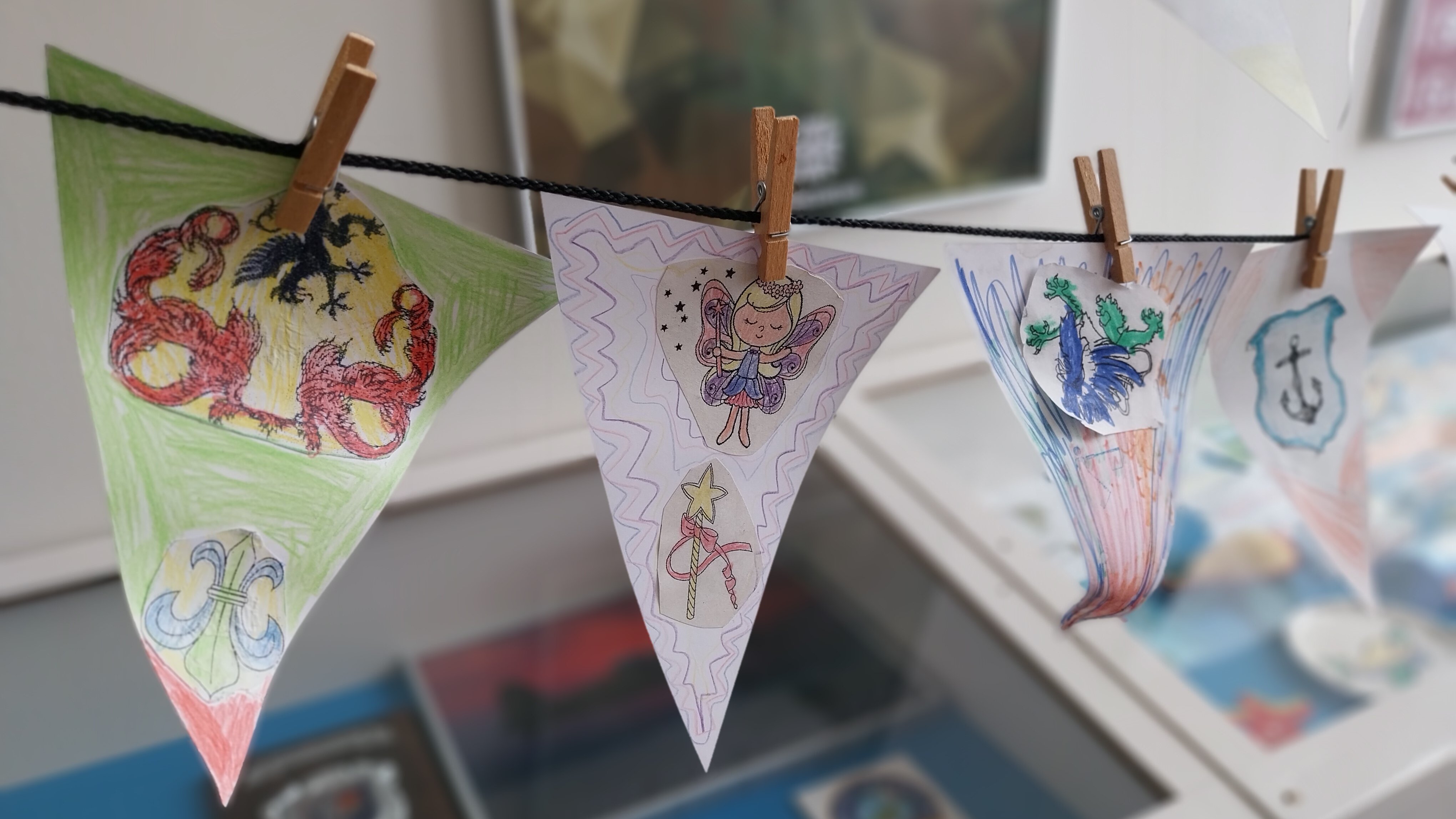 Bunte Wimpel mit verschiedenen Symbolen hängen mit Wäscheklammern befestigt auf der Leine. 