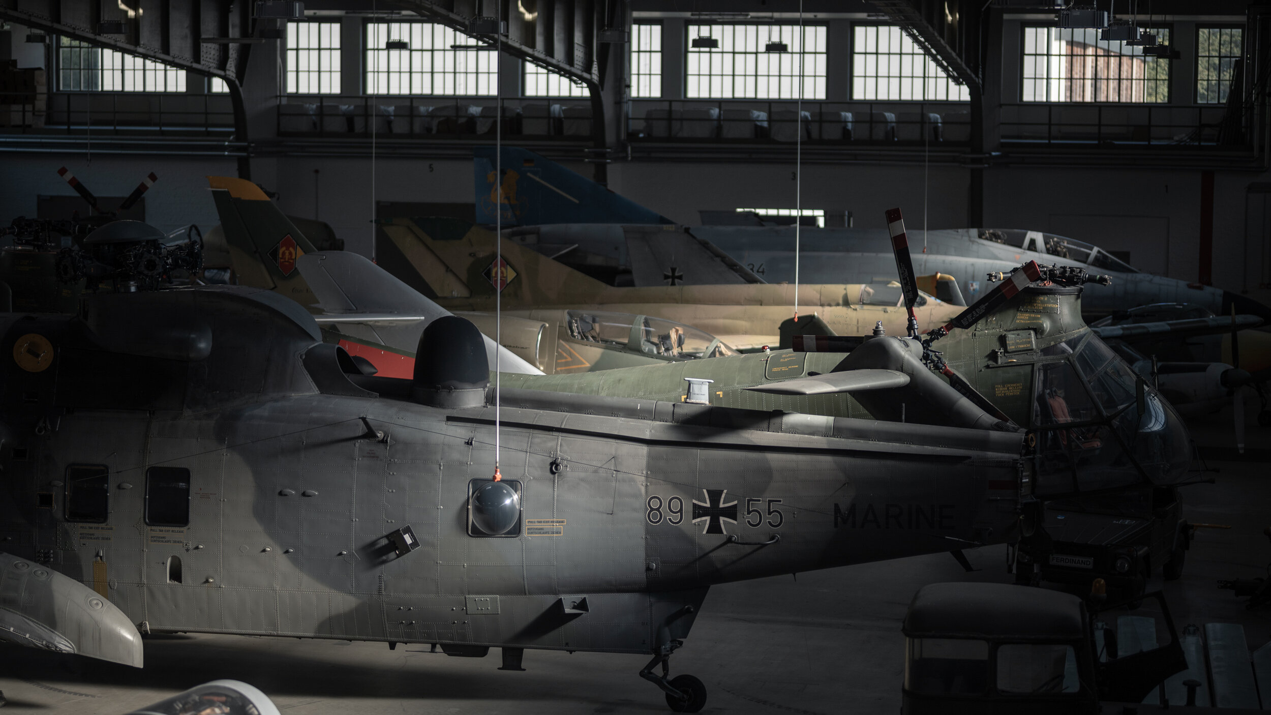 Helikopter und Flugzeuge in Seitenansicht im Depothangar. 