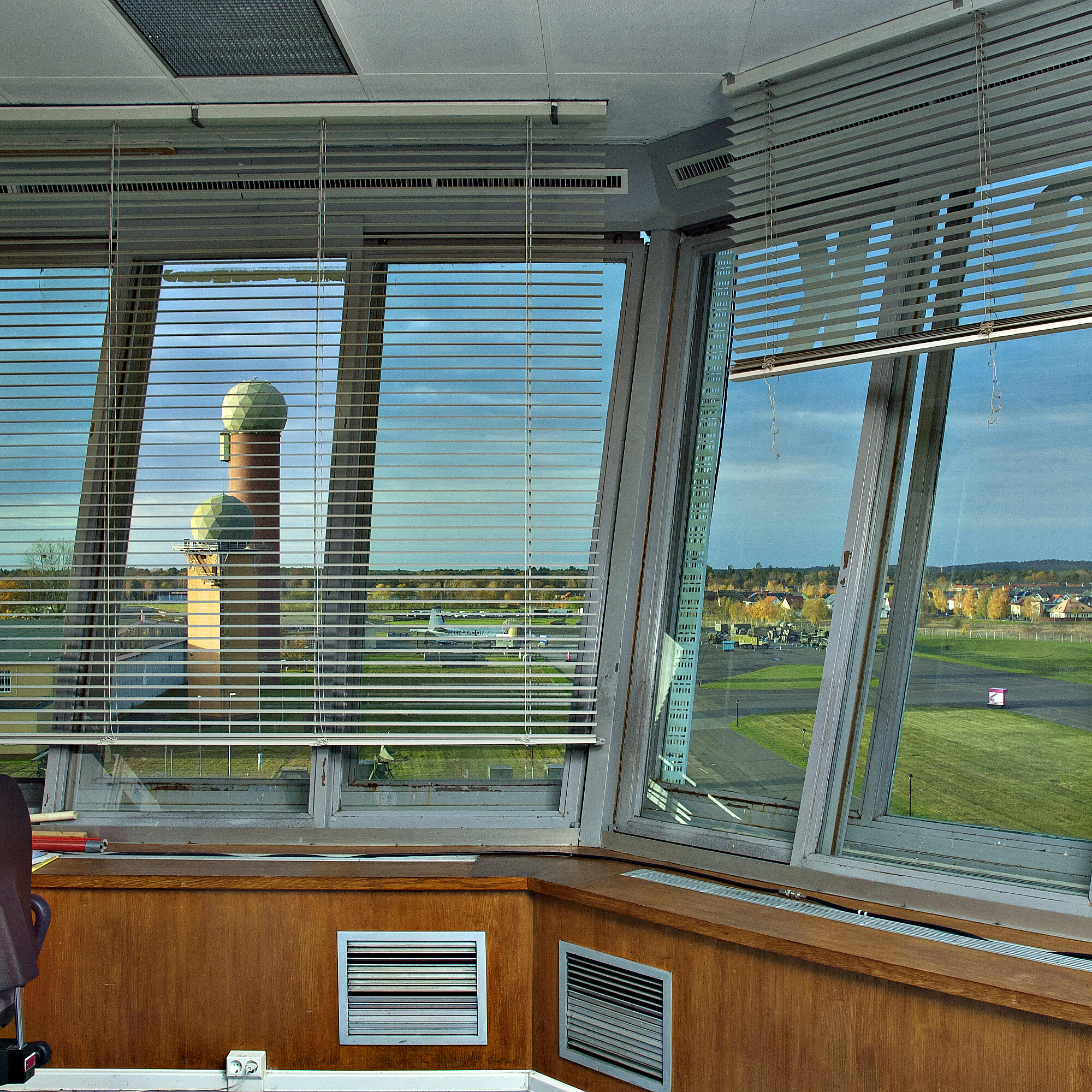 Blick durch die Fenster der Towerkanzel auf das Gelände mit Hangar 4 und Radartürmen. 
