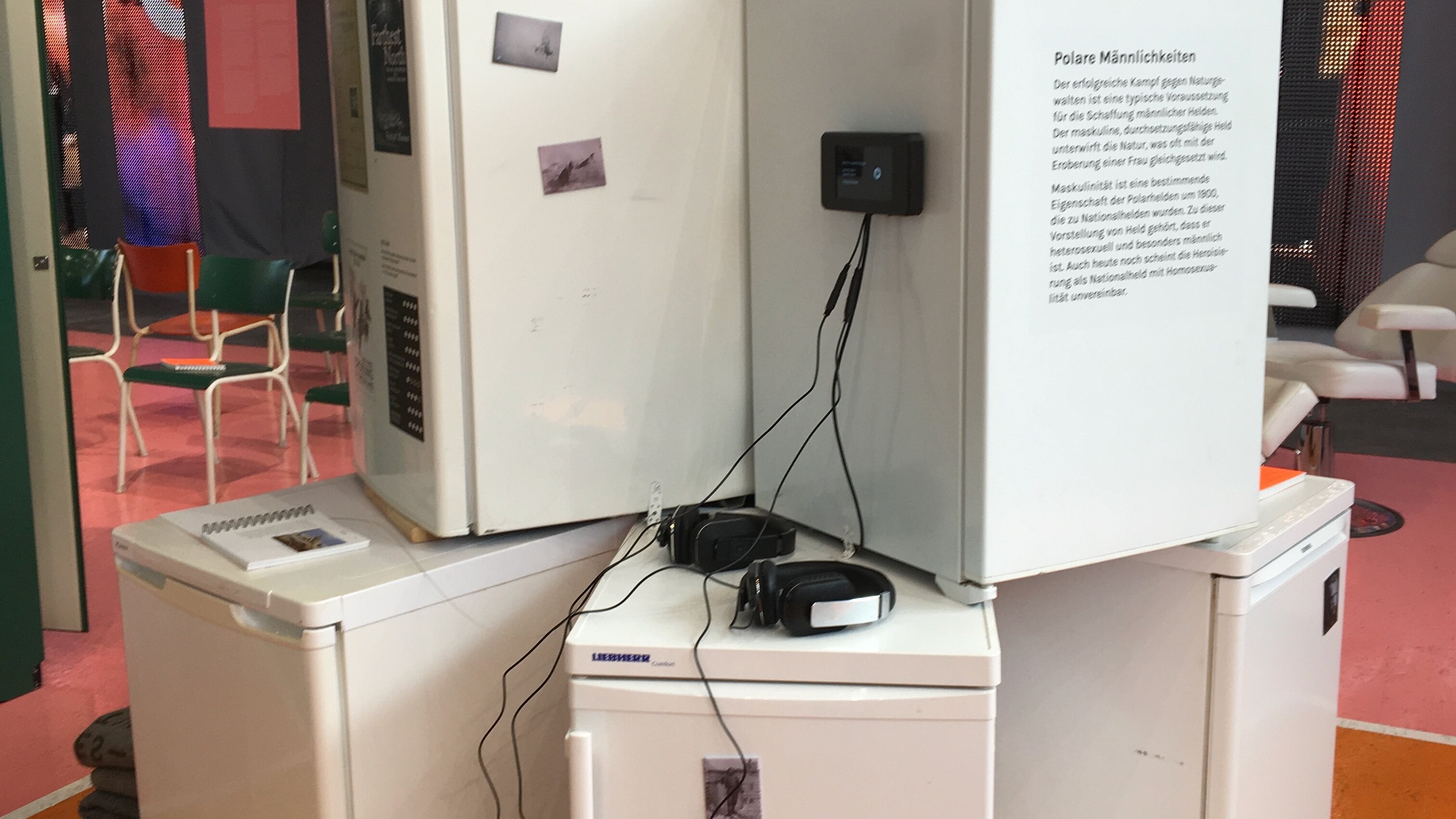 Ein Stapel aus Kühlschränken mit Bildmagneten und Texttafel. 
