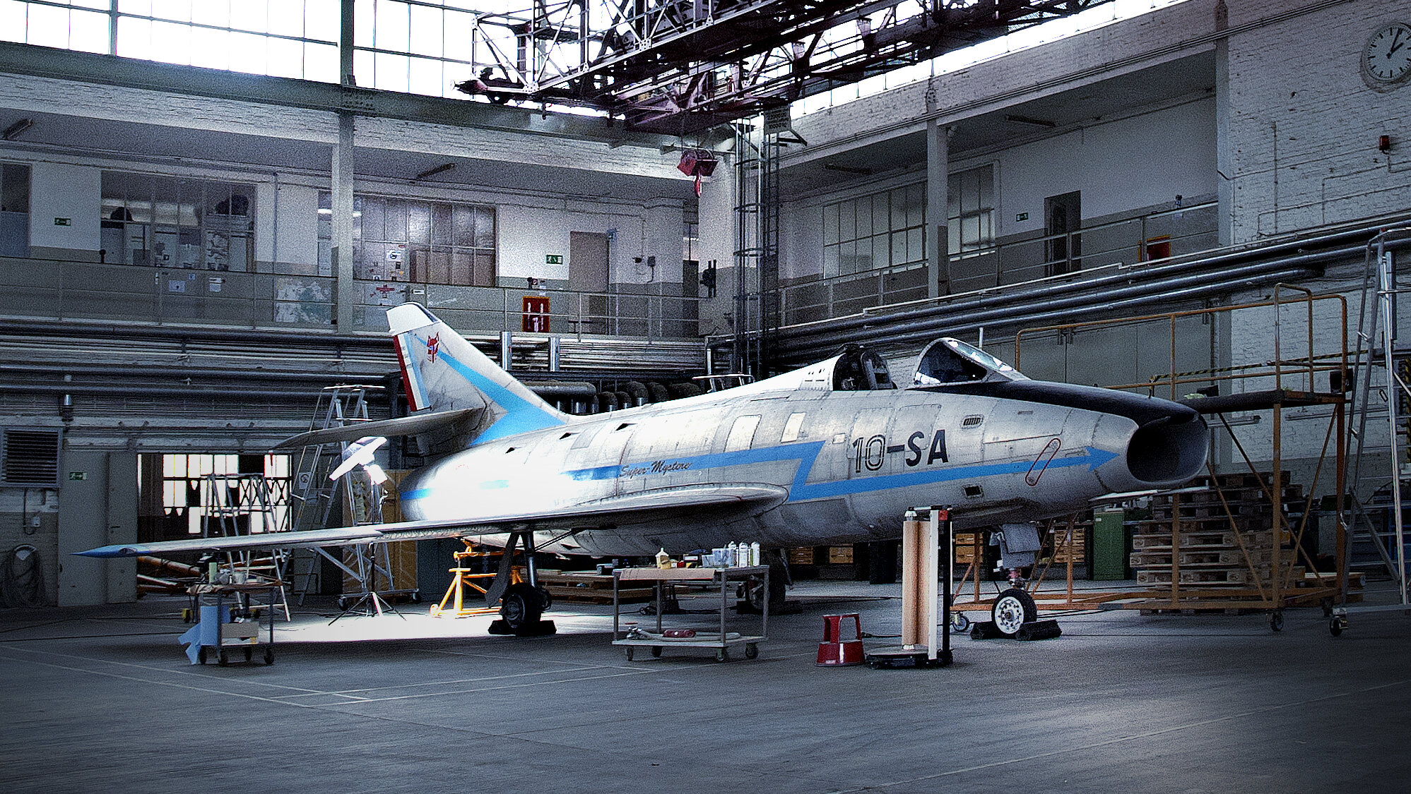 Das hochrechteckige Foto zeigt ein Flugzeug in einem hohen Hangar. 