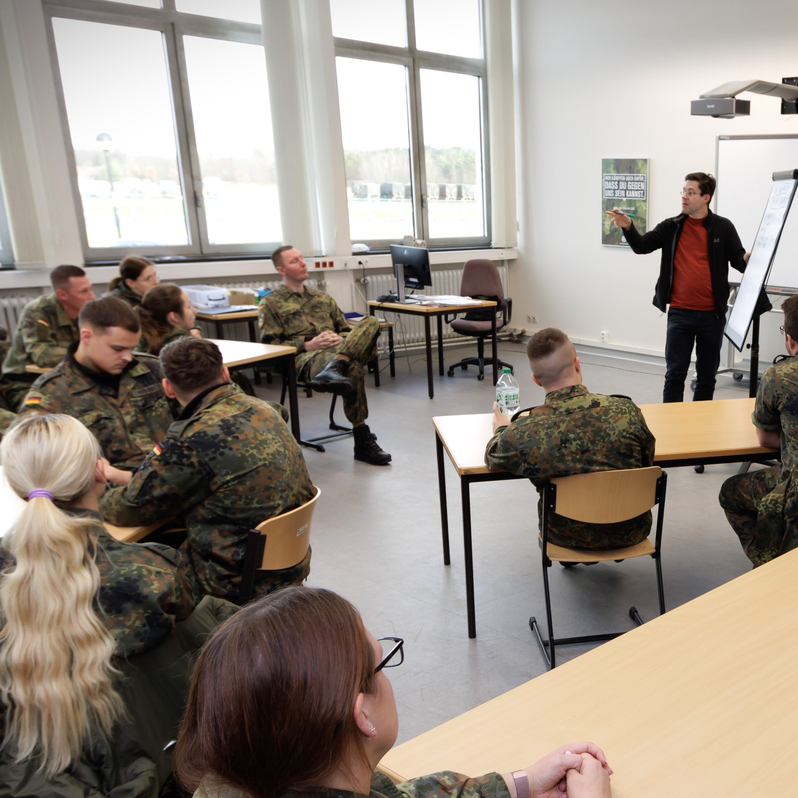 A group of German soldiers in field uniform with their civilian lecturer in a seminar room. 