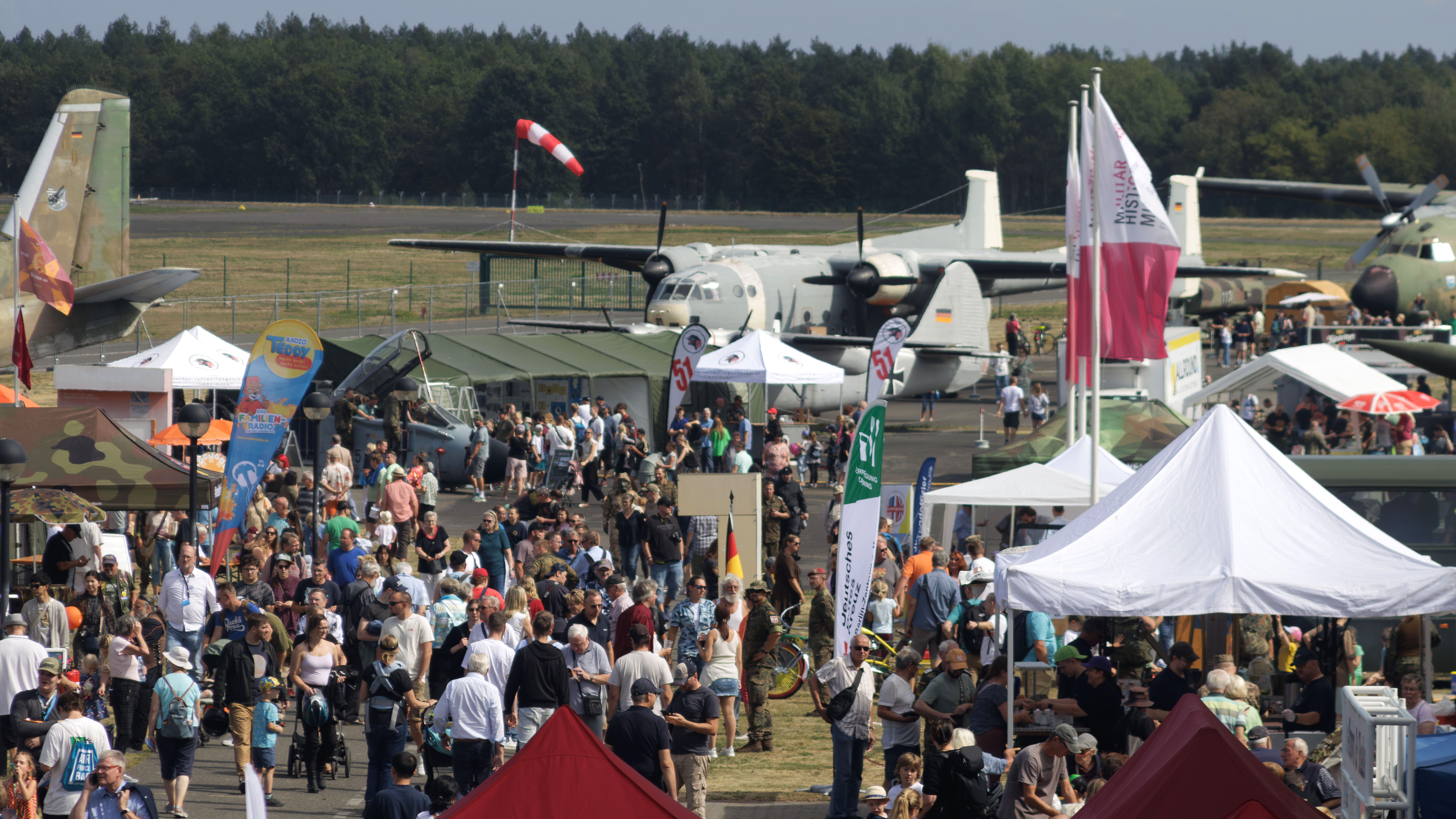 Blick auf das Flugplatzfest mit Menschenmenge, Ständen und Flugzeugen.  