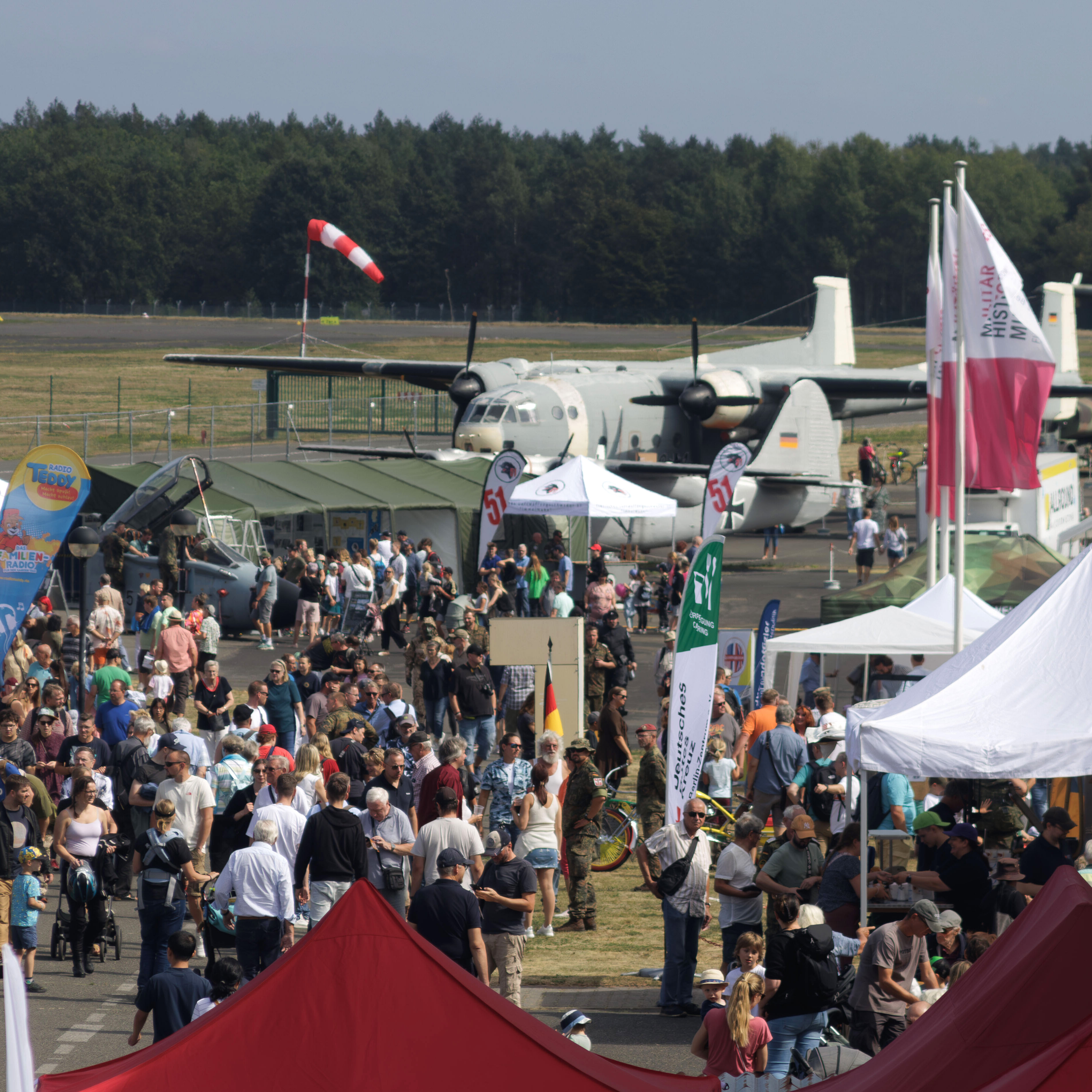 Blick auf das Flugplatzfest mit Menschenmenge, Ständen und Flugzeugen.  
